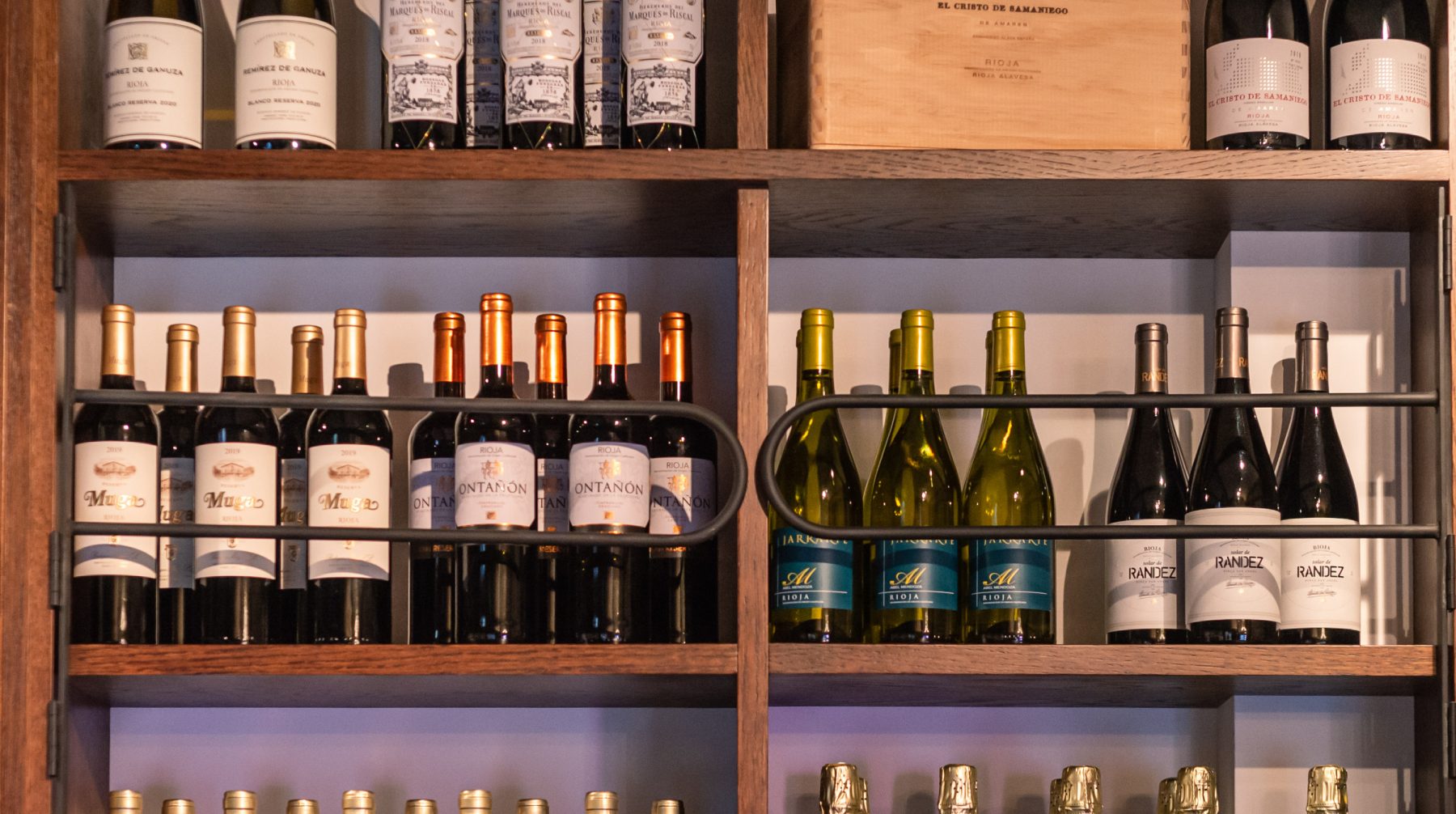 Close up image of wine bottles in a wooden shelving unit.